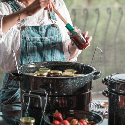 Person making homemade jam with strawberries and jars.